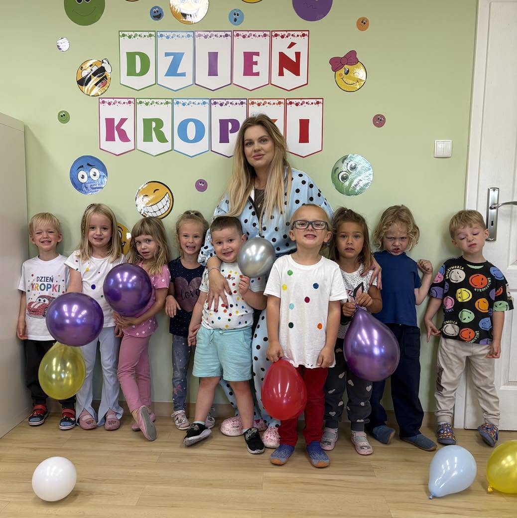 Grupa dzieci z wychowawczynią i kolorowymi balonami podczas Dnia Kropki w Krainie Uśmiechu