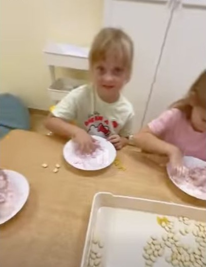 Dzieci podczas zabawy sensorycznej z pianką i różnymi materiałami w przedszkolu przy Różowej.