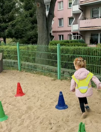 Zabawa ruchowa między kolorowymi pachołkami na placu zabaw Krainy Uśmiechu